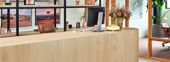 Formica Natural White Oak Wooden reception desk with computer and decor in a modern office setting